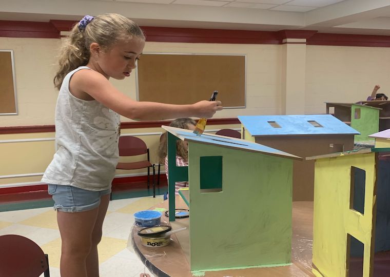 Camper painting her dollhouse